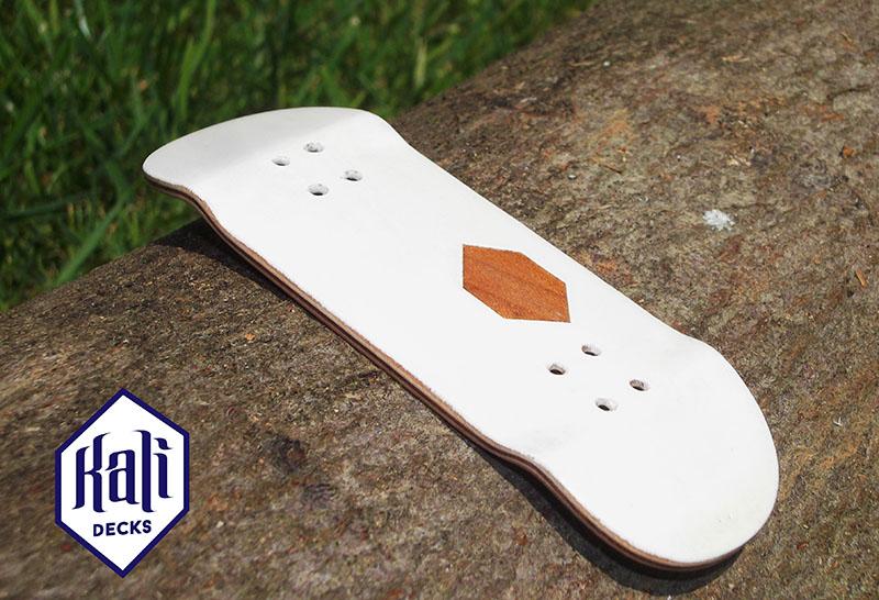 Kali Fingerboard Deck from 2016 with a framing white paint above a cherry wood wooden ply